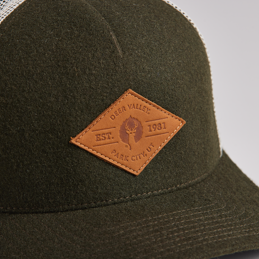 upclose of leather logo on 5 panel wool trucker hat with adjustable snapback